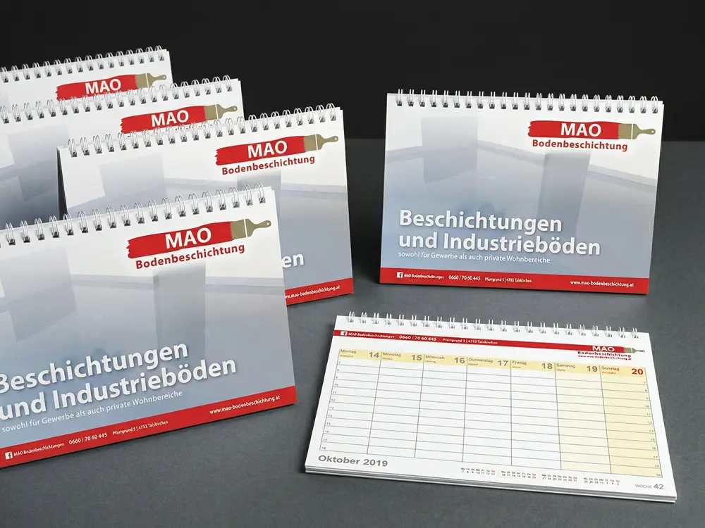 Wochen-Tischkalender mit individuell bedrucktem Deckblatt und frei gestaltbarem Innenteil, gefertigt mit hochwertiger Spiralbindung in verschiedenen Farben.