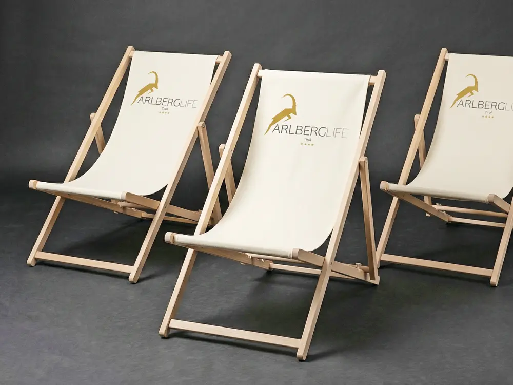 Klassische Indoor-Liegestühle mit Werbeaufdruck und B1-zertifizierter Textilbespannung und verstellbarer Lehne für den Hotelbereich.