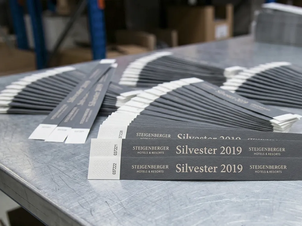 Hochwertige Tyvekkontrollbänder mit silberfarbenem Aufdruck für exklusive Events, Hotels und Gastronomie zur reißfesten Gäste-Identifikation.