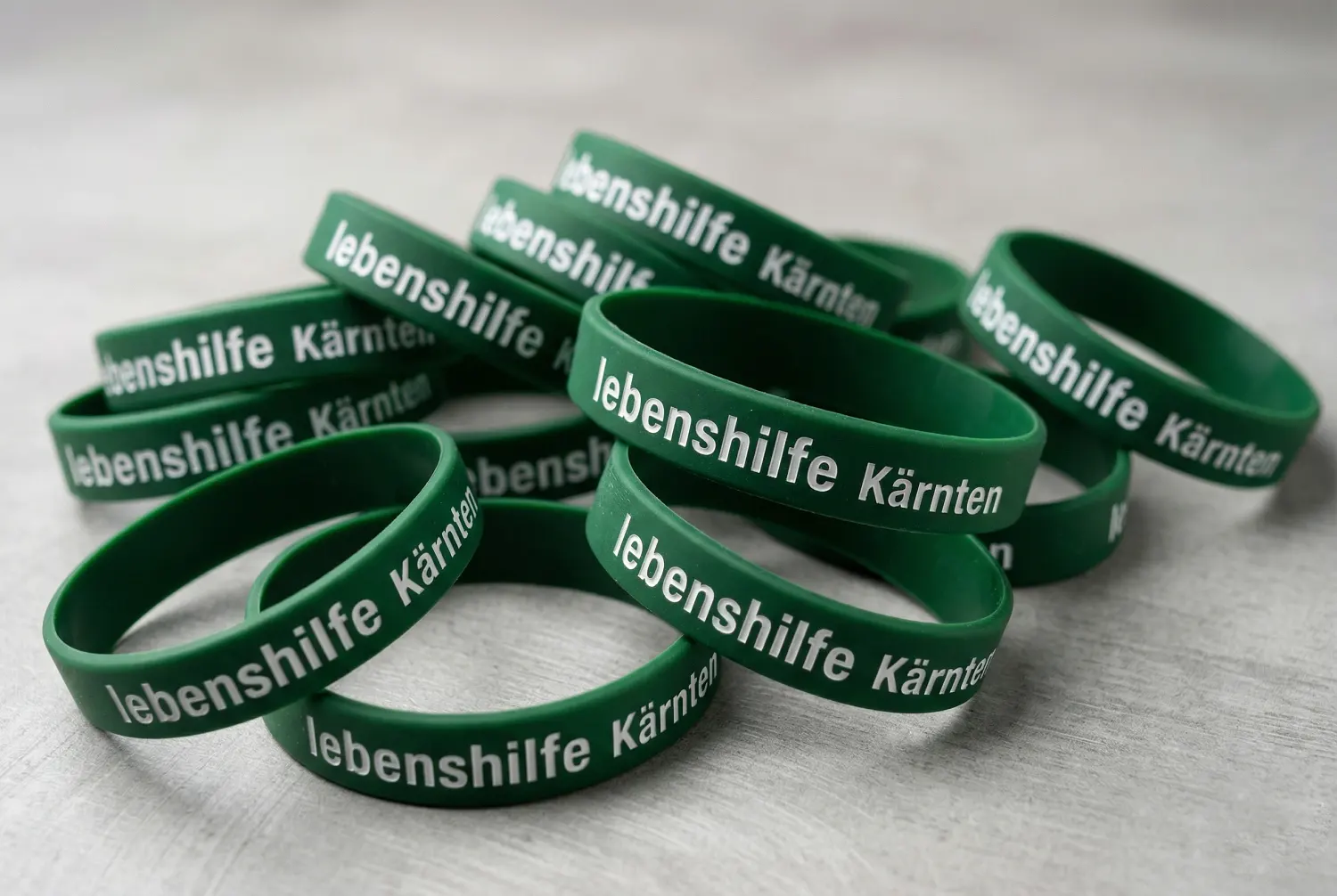 Produktion von individuell bedruckten Silikonarmbändern für die Lebenshilfe Kärnten: Umsetzung von Event- und Merchandising-Artikeln durch infinite.